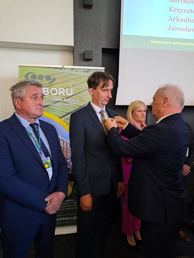 Minister Kołakowski wręczający starszemu specjaliście Danielowi Krauklisowi  odznakę „Zasłużony dla Rolnictwa”