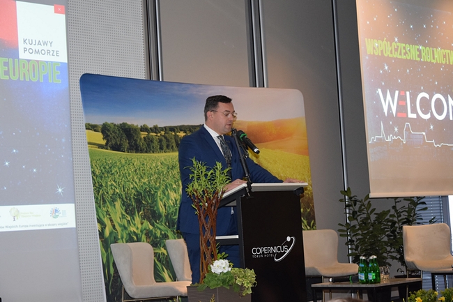 Wiceminister Rolnictwa i Rozwoju Wsi Stefan Krajewski, stojący na głównej scenie za mównicą na tle banerów reklamowych